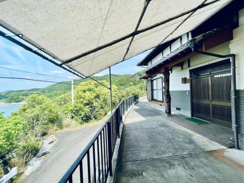 a building with a balcony with a view of the water at ぽつんとオーシャンビューでバーベキューも出来る1日1組貸切宿カゴヤブハウス in Otsuki