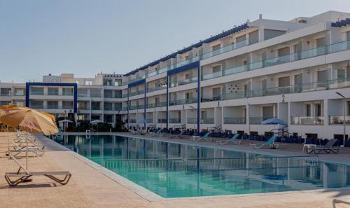 a hotel with a swimming pool with chairs and an umbrella at Adan appartement in Aourir