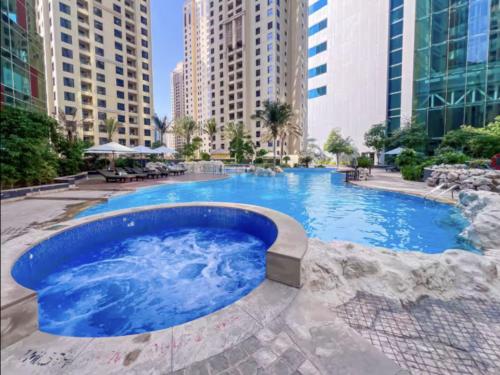 a large swimming pool in a city with tall buildings at JBR Coastal Escape - Amazing Sea Views, Pool & State-of-the-Art Gym in Dubai