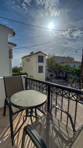 a table and chairs sitting on a balcony at Melinda’s cozy apartments in Plomarion