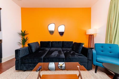 - un salon avec un canapé noir et un mur orange dans l'établissement 30A Modern Suite with King Bed, Parking, Pool and Balcony, à Santa Rosa Beach