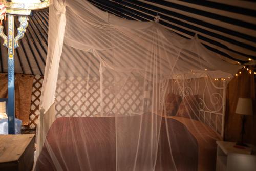 a canopy bed with white curtains in a room at Eco Glamping Portugal Nature Lodge in São Luis