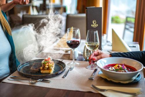 a table with a plate of food and two glasses of wine at Barack Thermal Hotel and Spa in Tiszakécske