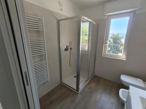 a bathroom with a shower and a toilet and a window at BEDE-Bike in Casazza