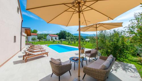 a patio with chairs and an umbrella and a pool at Holiday Home The Olive Escape in Stolac