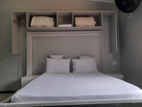 a small bedroom with a bed with white sheets and pillows at Silent Night Guest House Sunnyside Pretoria in Pretoria