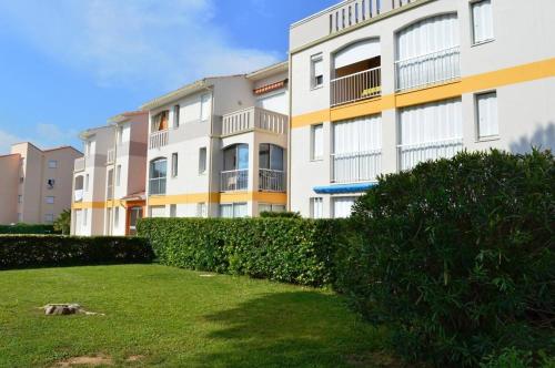un grand immeuble d'appartements avec une haie en face dans l'établissement Appartement Studio cabine 4 couchages ARGELES SUR MER AR020-027, à Argelès-sur-Mer
