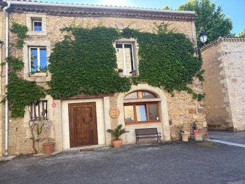 un bâtiment avec une porte et un banc devant lui dans l'établissement Ô banc de la vigne, à Fabrezan