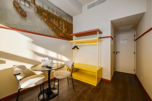 a room with a table and chairs and a yellow desk at The Queen's Twelve by Romy&Travis in Bruges