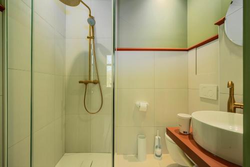 a bathroom with a glass shower and a sink at The Queen's Twelve by Romy&Travis in Bruges