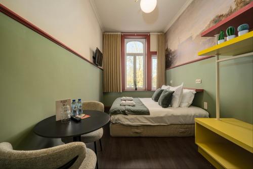 a bedroom with a bed and a table and chairs at The Queen's Twelve by Romy&Travis in Bruges