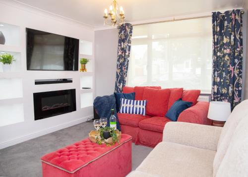 a living room with a red couch and a tv at Stylish and Spacious 3-Bed House Free Parking in Ipswich