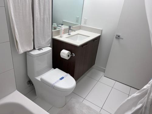 une salle de bains blanche avec toilettes et lavabo dans l'établissement Master Bedroom In CALLE OCHO, à Miami