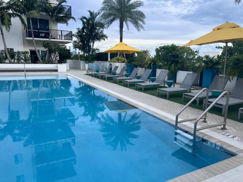 une piscine avec chaises et parasols dans un hôtel dans l'établissement Master Bedroom In CALLE OCHO, à Miami