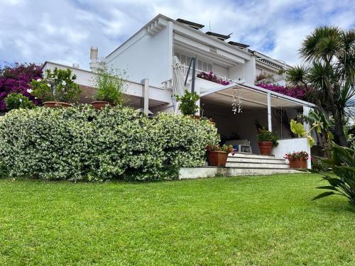 a white house with potted plants in a yard at Casa de la Luna in Nettuno