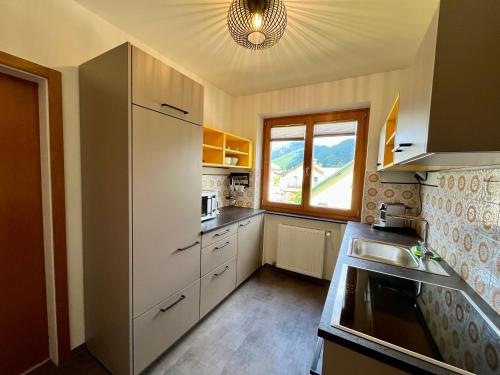 a kitchen with white cabinets and a large window at Salzkammergut Hideaway RUDOLPH in Bad Ischl