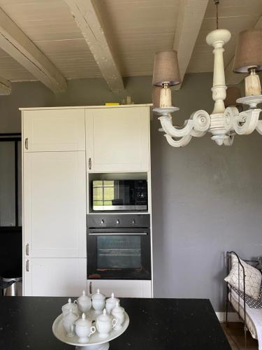 une cuisine avec une table avec des tasses et un four dans l'établissement La Grange, gîte de campagne proche Benon et La Rochelle, à Saint-Georges-du-Bois