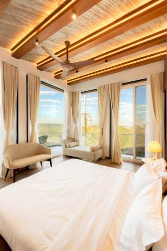 a bedroom with a large bed and large windows at Kyomi Retreat-Mukteshwar in Mukteswar