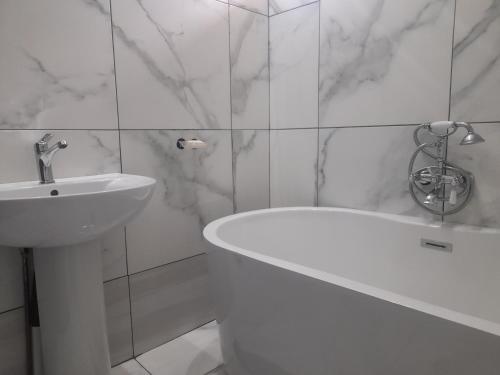 a white bathroom with a sink and a bath tub at Silent Night Guest House Sunnyside Pretoria in Pretoria