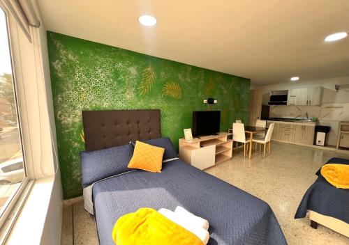 a bedroom with a blue bed and a green wall at PARK 66 Apartaestudios in Cali