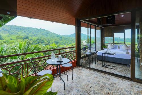 a hotel room with a bed and tables and windows at Nestay in Karnāla