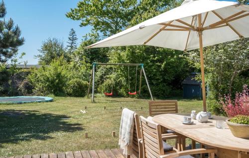 a table with an umbrella and a swing at Stunning Home In Sjællands Odde in Yderby