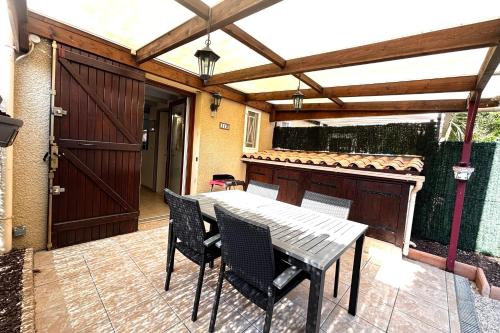 d'une terrasse avec une table, des chaises et une porte. dans l'établissement Le Hameau - Proche plage - Piscine - Parking, à Saint-Cyprien