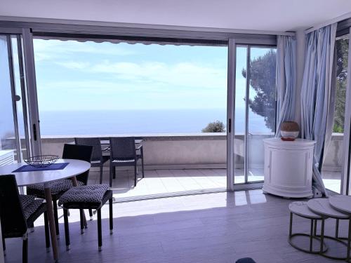 a room with a balcony with tables and chairs at Sunny Home Costa Plana-Monaco -Cap D'Ail in Cap d'Ail