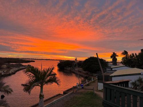 a sunset over a body of water with palm trees at Pelican Point Waterfront Resort in Carnarvon
