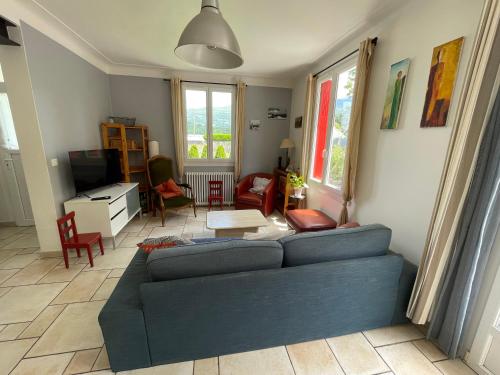 een woonkamer met een blauwe bank en een tv bij Grande maison dans les Pyrénées in Argelès-Gazost