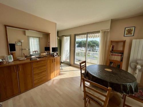 a living room with a table and a kitchen with a window at Appartement 3 pièces proche de la plage avec parking - FR-1-494-146 in Royan