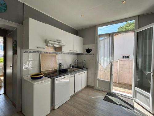 une cuisine avec des placards blancs et une grande fenêtre dans l'établissement Villa 1926 à Royan/Pontaillac, proche plage et commerces, 3 ch, parking privé, cuisine équipée. - FR-1-494-147, à Royan