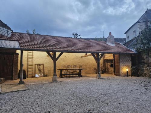 a pavilion with a table and a bench in a courtyard at La parenthèse-Logement cosy et Luxueux in Veuzain-sur-Loire