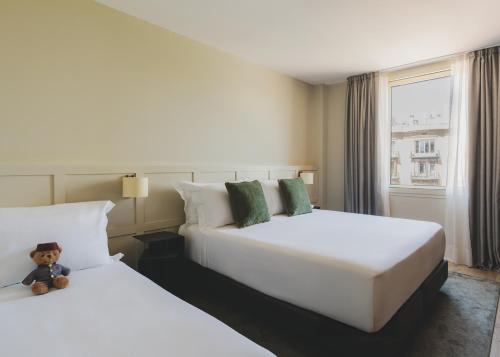 two beds in a hotel room with a teddy bear sitting between them at Gallery Hotel 4 Sup in Barcelona
