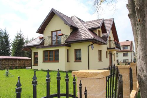 a house with a black fence in front of it at Pokoje Gościnne Сisza in Białowieża