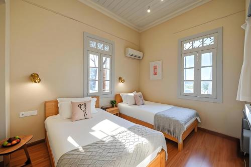 two beds in a room with two windows at Gulangyu Liuyue Garden Resort Hotel in Xiamen
