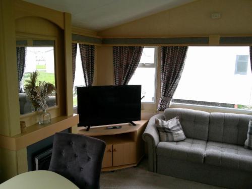 a living room with a couch and a television at Eastgate Richmond 8 Berth Blow Heated Free WIFI in Ingoldmells