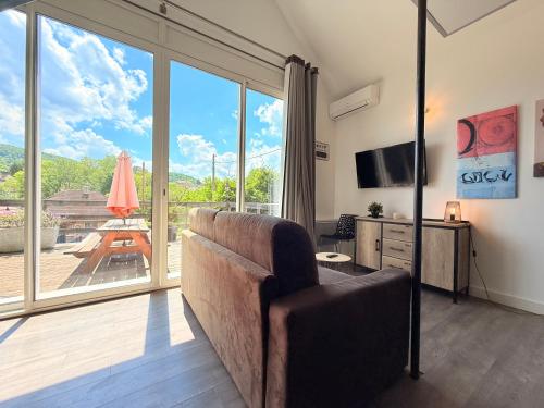 a living room with a couch and a large window at Les terrasses d'Ornans in Ornans