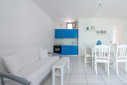 a white living room with blue cabinets and a table and chairs at Case Vacanze Otranto in Otranto