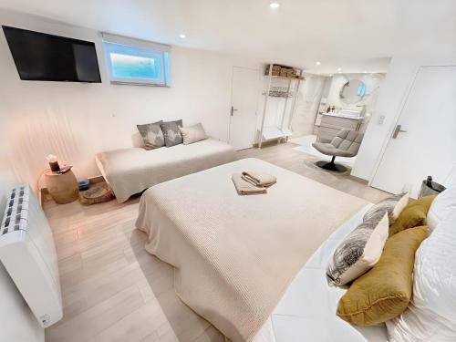 Cette grande chambre blanche comprend deux lits et un canapé. dans l'établissement Appartement les Marinières, à Deauville