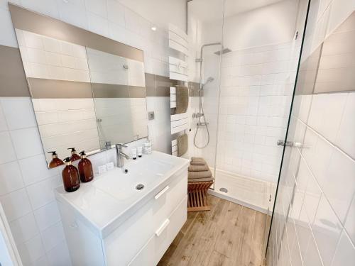 une salle de bain blanche avec un lavabo et une douche dans l'établissement Appartement les Marinières, à Deauville