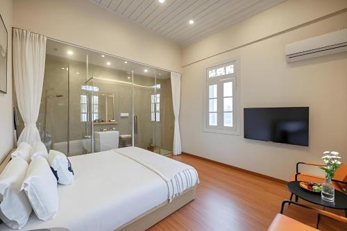 a bedroom with a large white bed and a tv at Gulangyu Liuyue Garden Resort Hotel in Xiamen