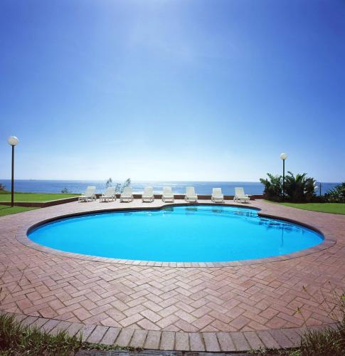 a swimming pool with chairs and the ocean in the background at Garden Court South Beach in Durban