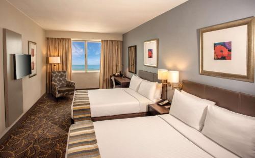 a hotel room with two beds and a chair at Garden Court South Beach in Durban