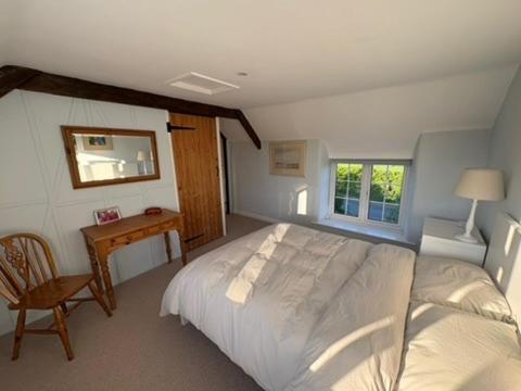ein Schlafzimmer mit einem Bett, einem Tisch und einem Stuhl in der Unterkunft Charming modernized country cottage Near Mere, Wiltshire in Mere