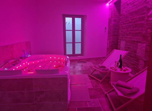 une chambre rose avec une baignoire et deux chaises dans l'établissement L'audacieuse-Jacuzzi et sauna , miroir suspendu, à Veuzain-sur-Loire