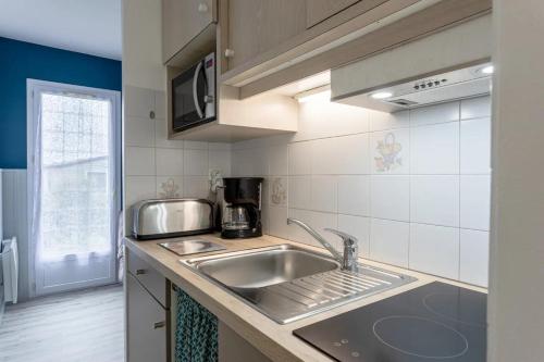 une cuisine avec un évier et un micro-ondes dans l'établissement Village Vacances Les Rivières, à Maché