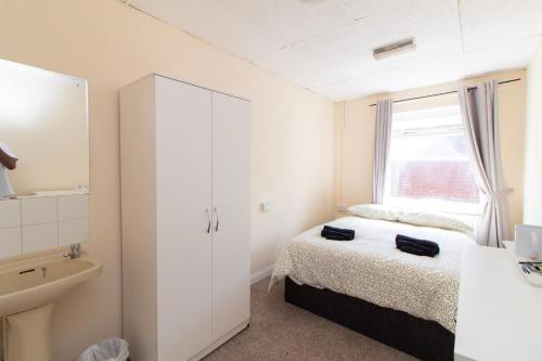 a small white bedroom with a bed and a window at Brookvale Guest House Room 4 in Southampton