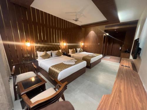 a hotel room with two beds and a television at Hyders Mahal & Hotel in Thanjāvūr
