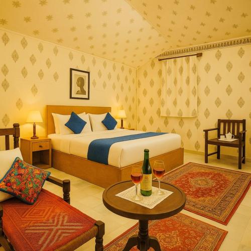 a bedroom with a bed and two glasses of wine at DESERT OVERNIGHT LUXURY CAMP & ReSORT in Jaisalmer